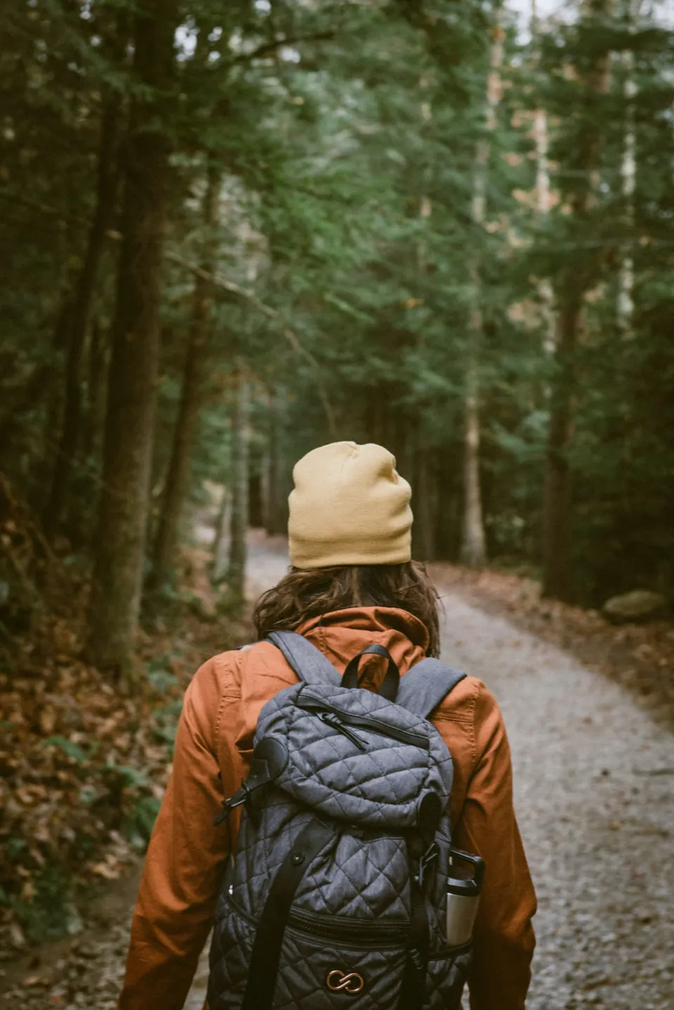 Woman carrying backpack towards the forest