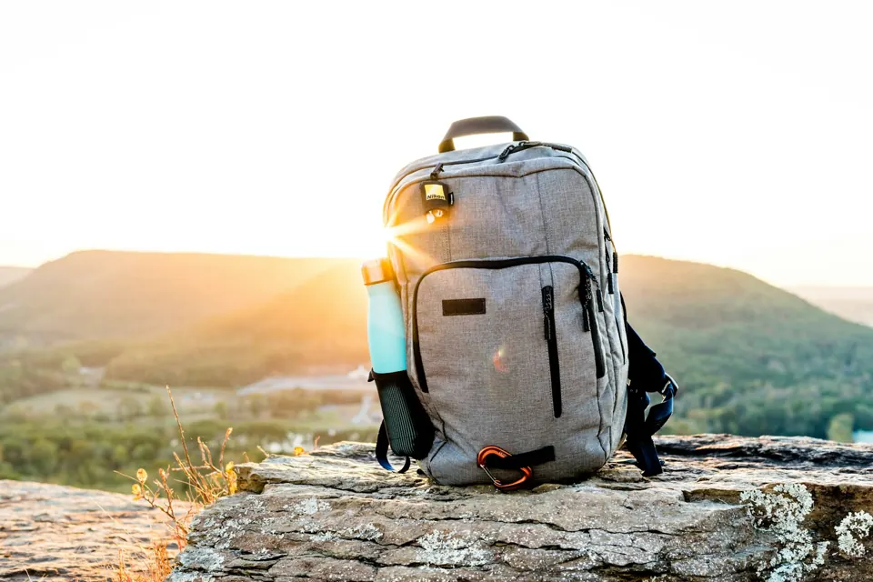 Grey and black hiking backpack on grey rock during sunset
