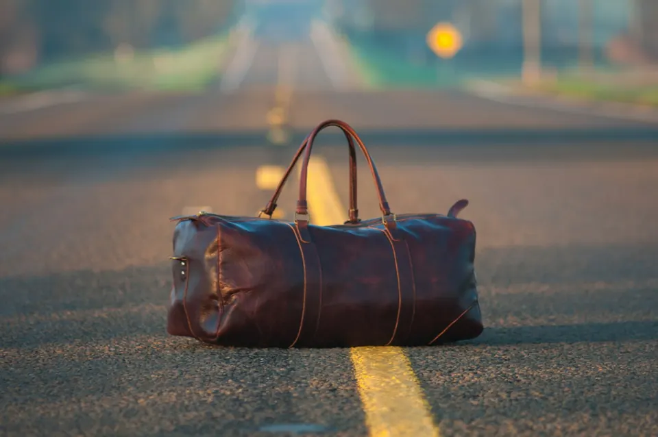 Brown leather duffel bag on a road