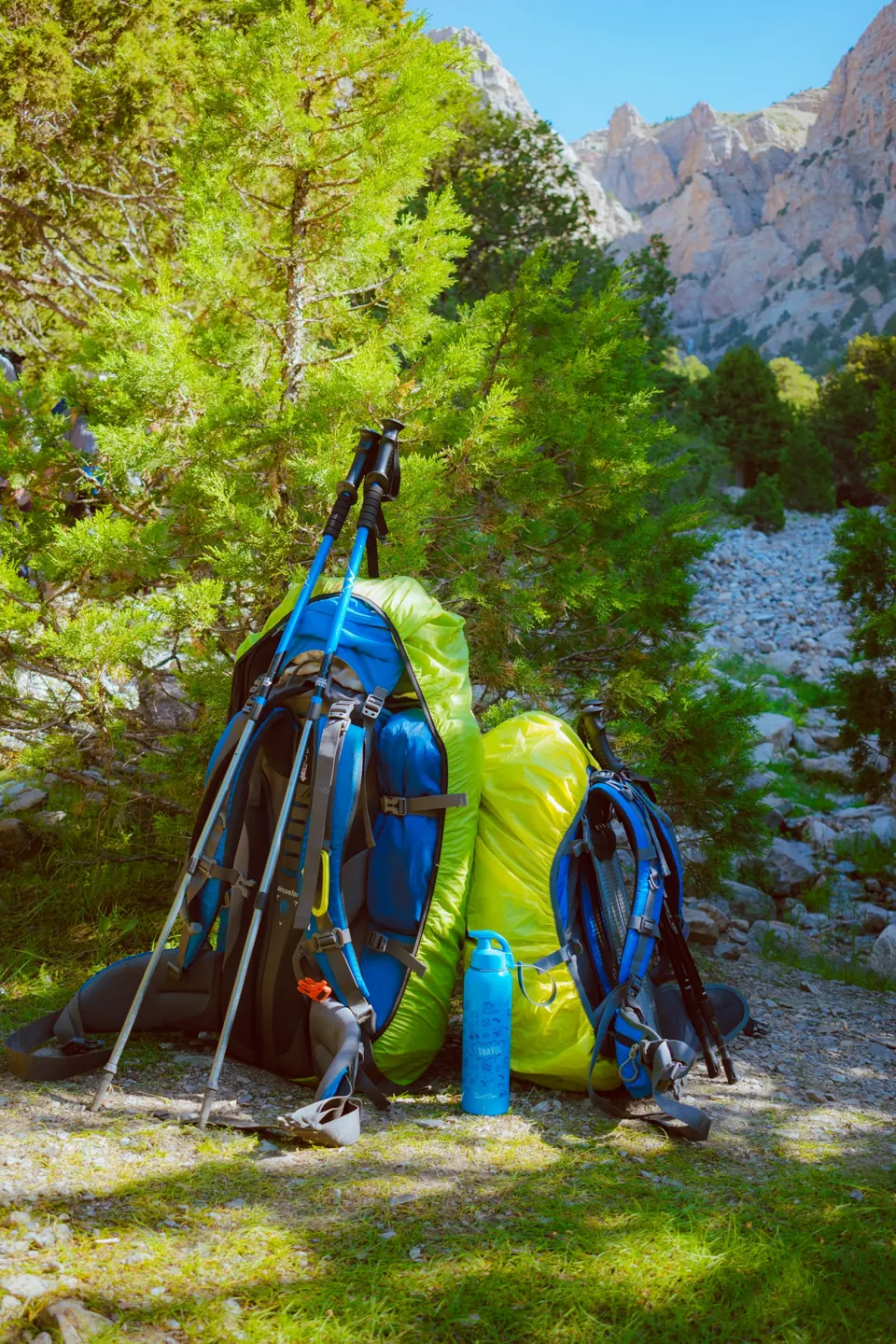 Blue and black hiking backpacks on rocky ground