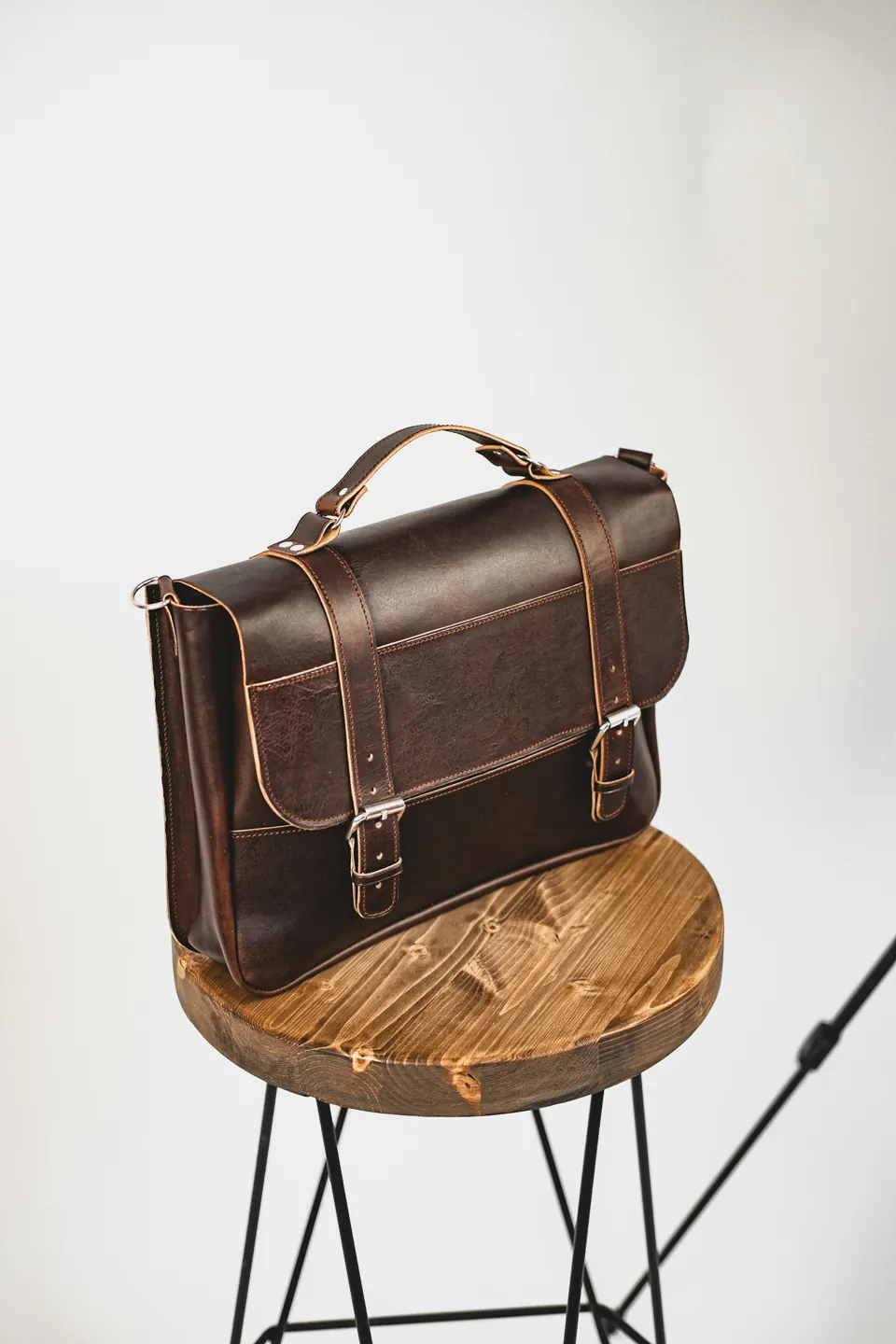Black leather sling bag on brown wooden round table