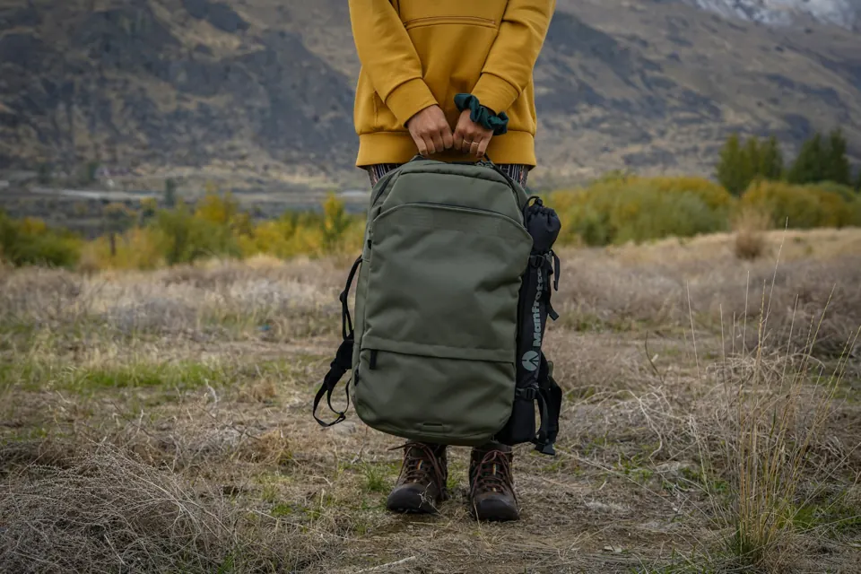 Person with black backpack on a grass field