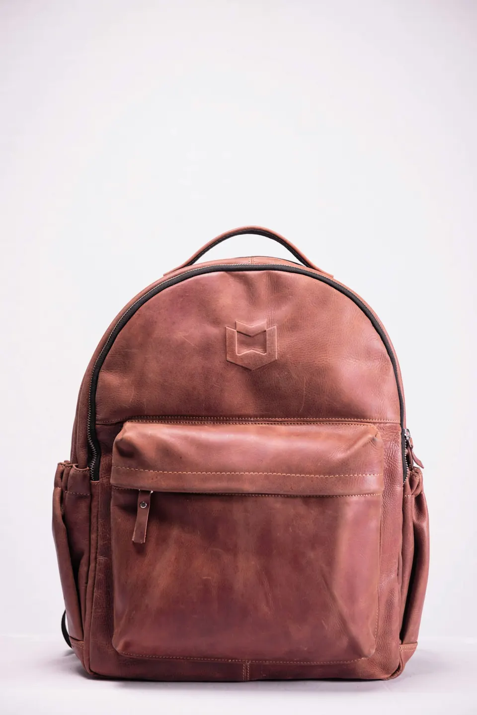 Brown leather backpack on white surface