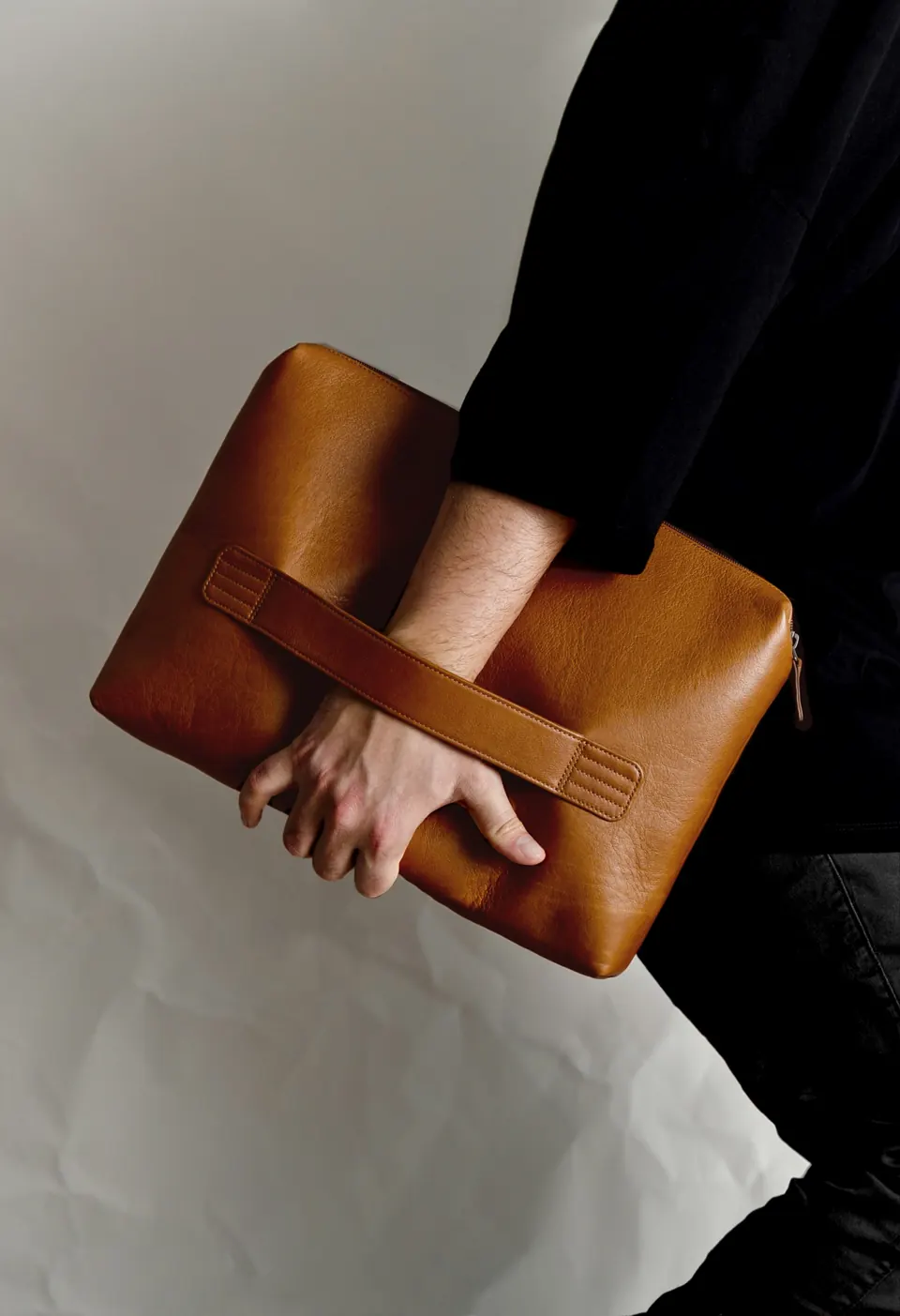 A person holding a brown leather briefcase