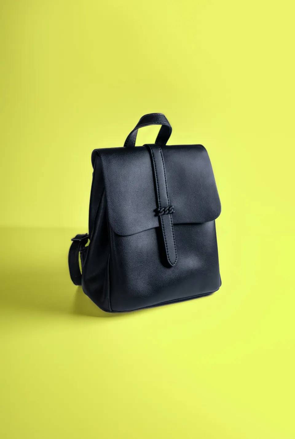A black leather backpack on a yellow background