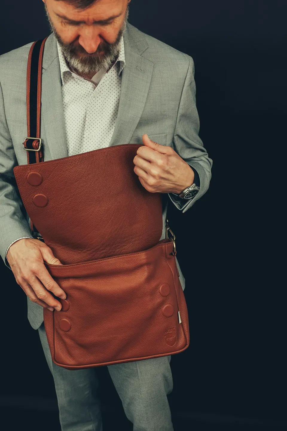 A man in a gray suit is holding a brown bag