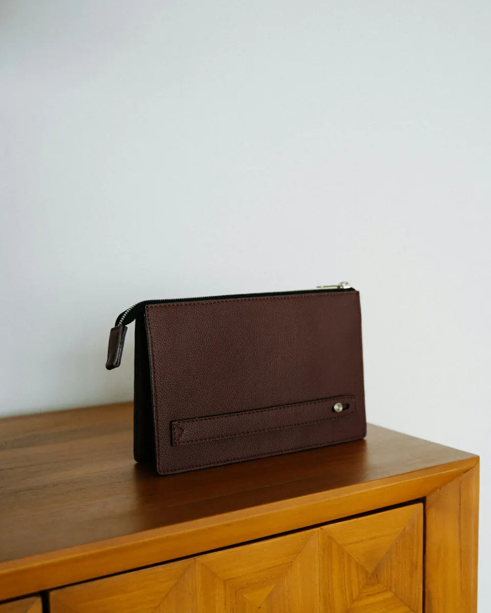 A brown leather clutch on a wooden surface
