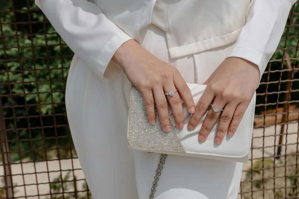 Hands holding a white beaded clutch bag